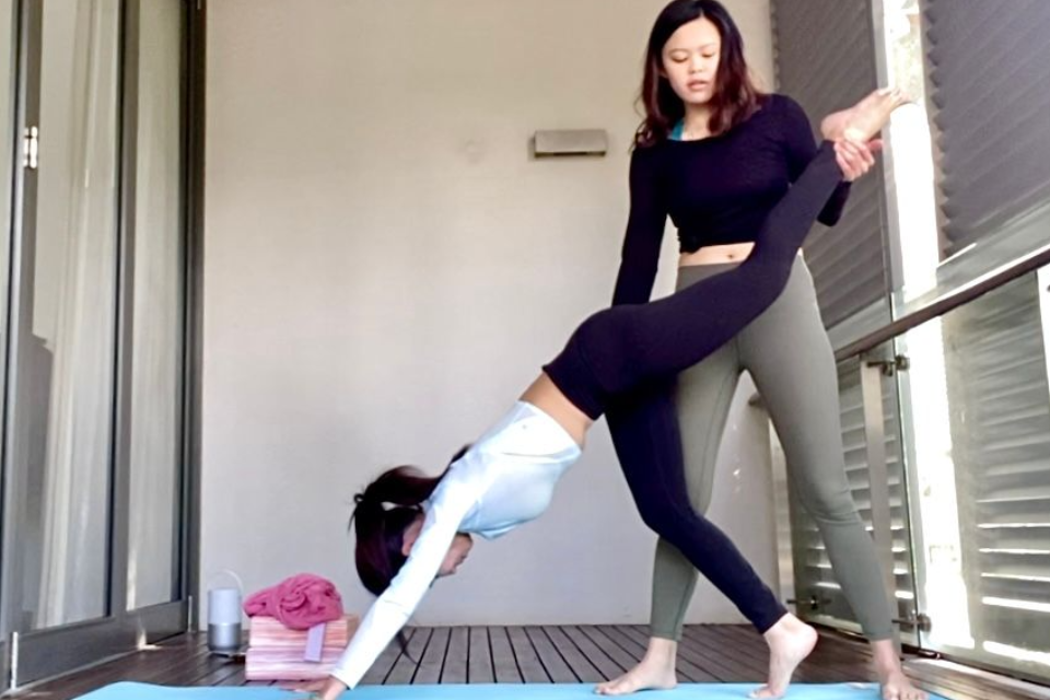 Emica guiding a student through a one-on-one yoga session